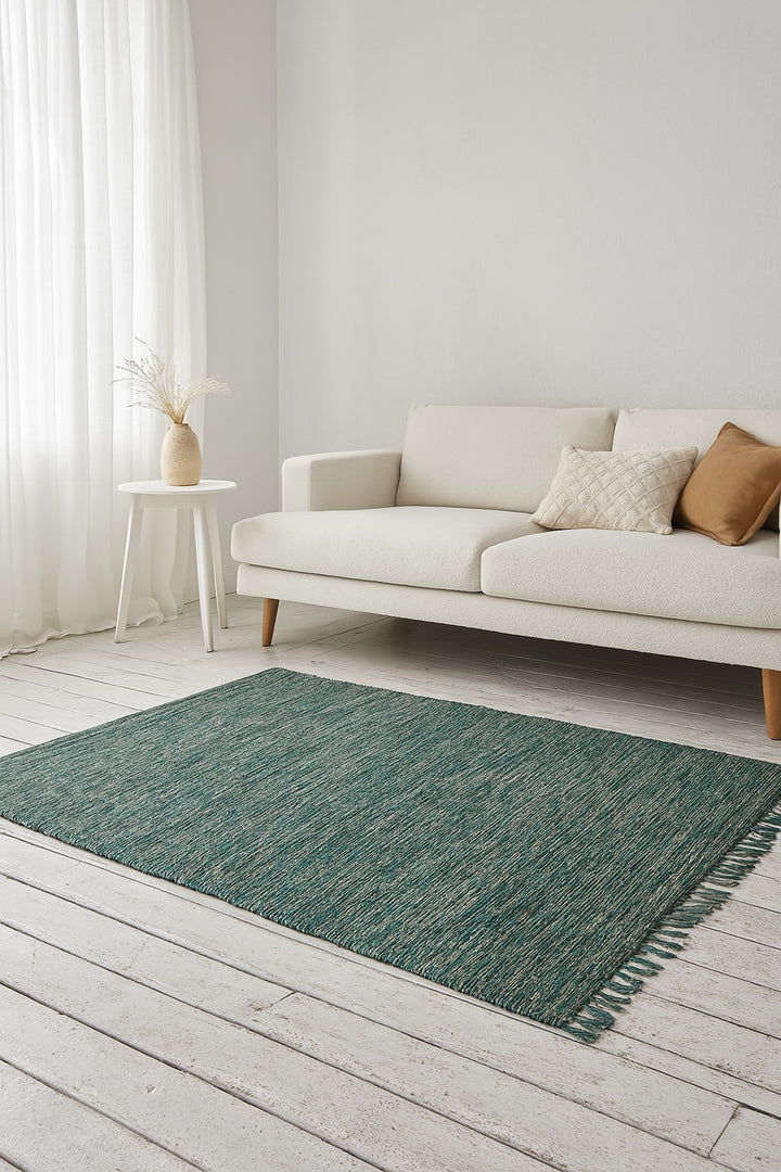 Green cotton rug in minimalist living room with white sofa, light wood floor and natural light from sheer curtains