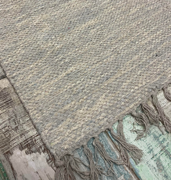 A Grey Drift Heavy Cotton Rug on a wooden floor.