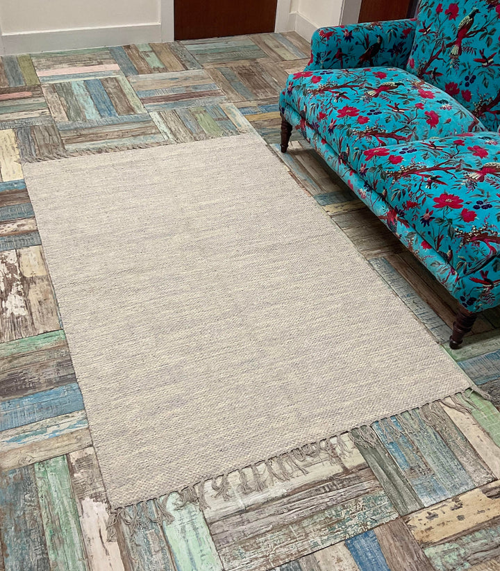 Grey Heavy Duty Cotton rug,on a wooden floor with a bird of paradise couch.