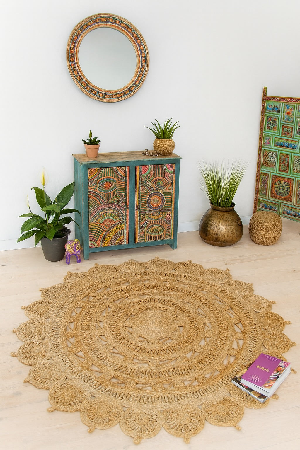 Round jute rug on a light wooden floor with decorative cabinet and plants in a room.