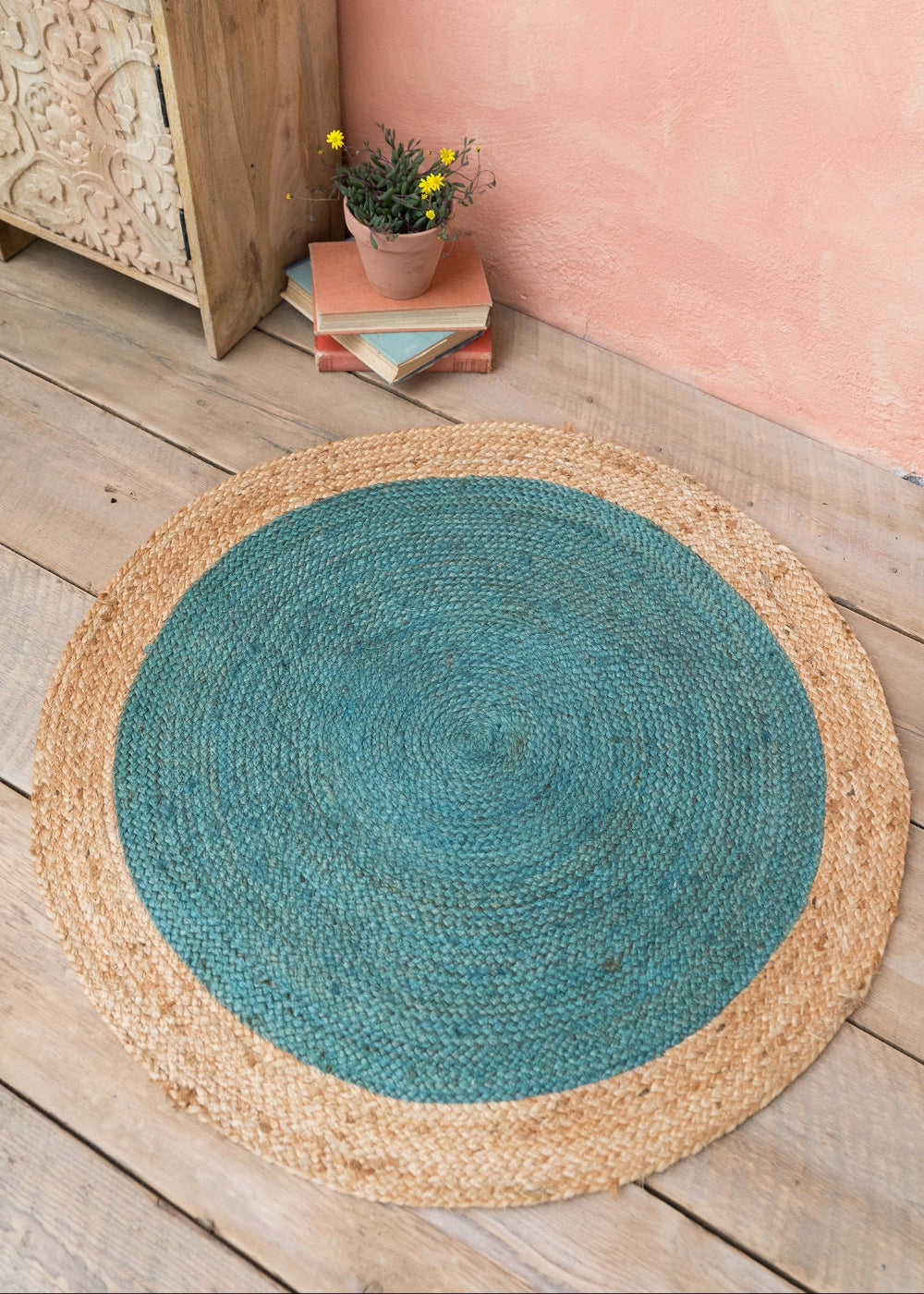 Round Blue rug with natural border on wooden floor against pink wall