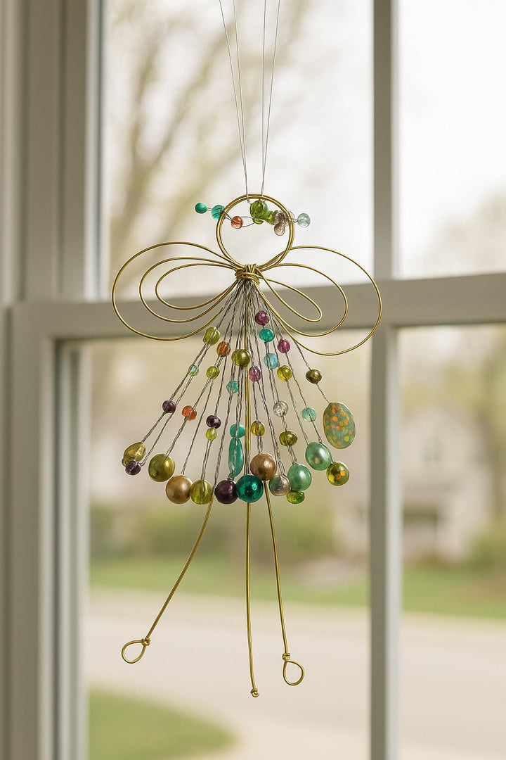 Decorative hanging angel with colourful beads in front of a window