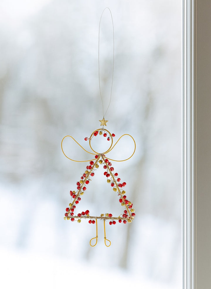 Decorative angel ornament with red beads on a white background