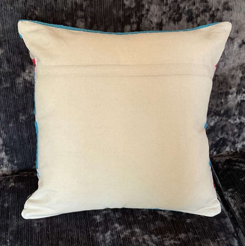 Beige pillow with blue trim on a textured dark surface