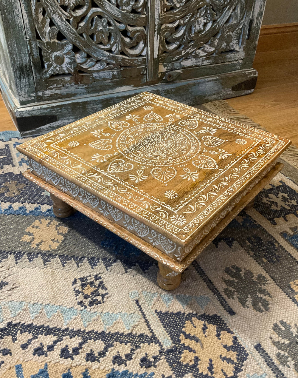 Decorative wooden box with intricate patterns on a textured rug
