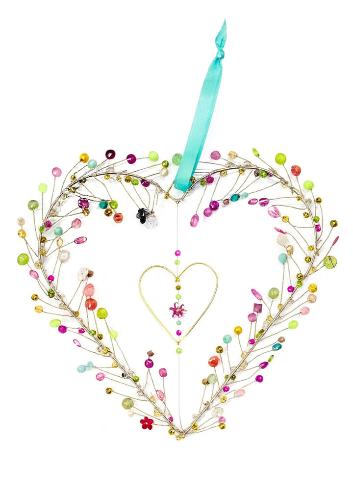 Decorative heart-shaped decoration with colourful beads and a blue ribbon on a white background