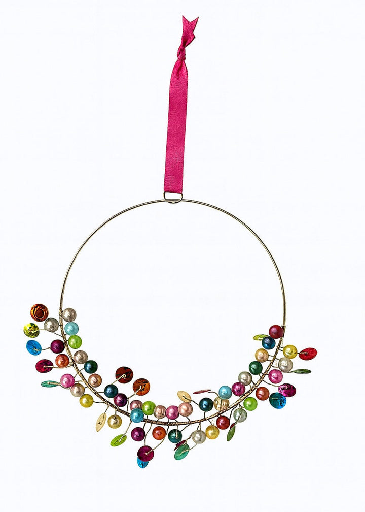 Decorative ring wreath hanging with colourful beads and a pink ribbon on a white background