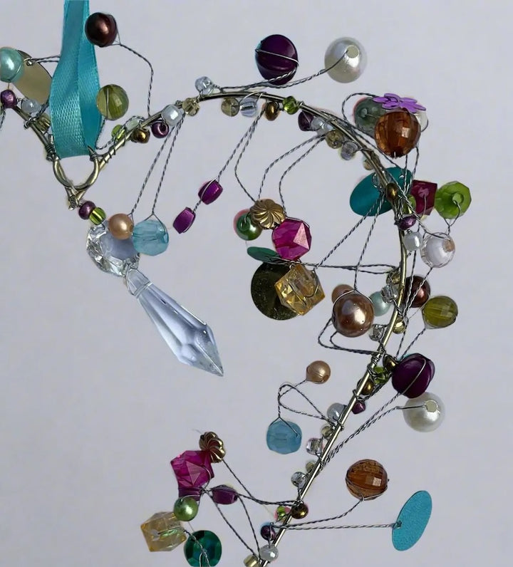 Colourful beaded heart decoration with various beads and a blue ribbon on a white background