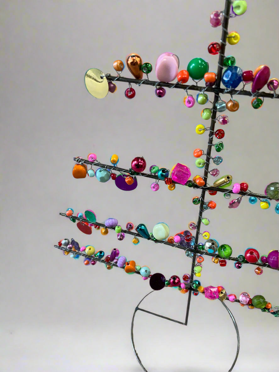 Colorful beaded tree sculpture on a plain background