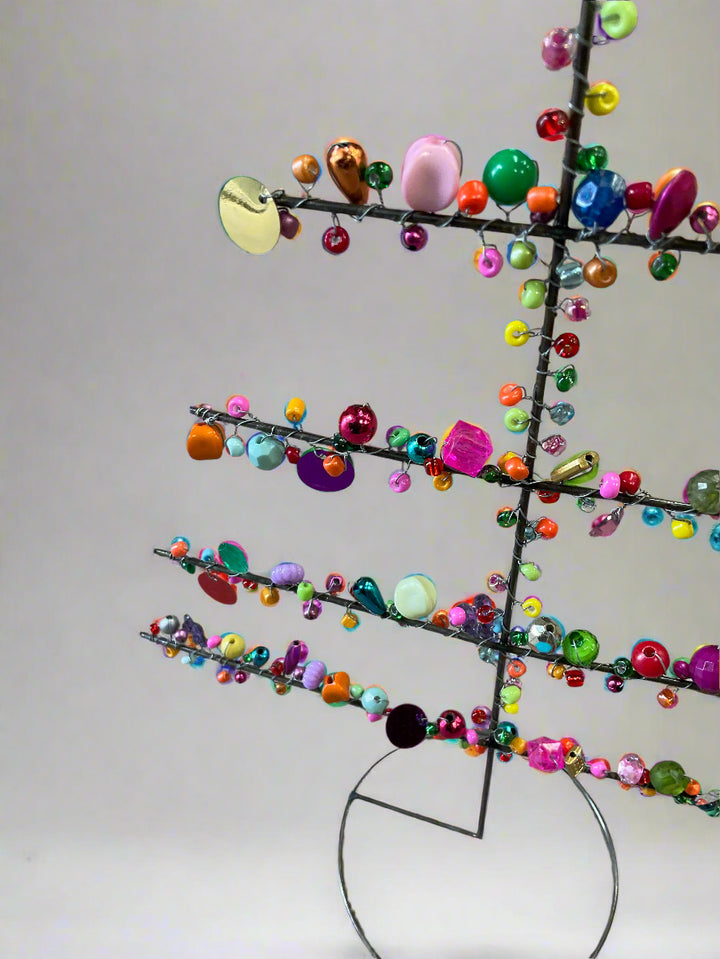 Colorful beaded tree sculpture on a plain background