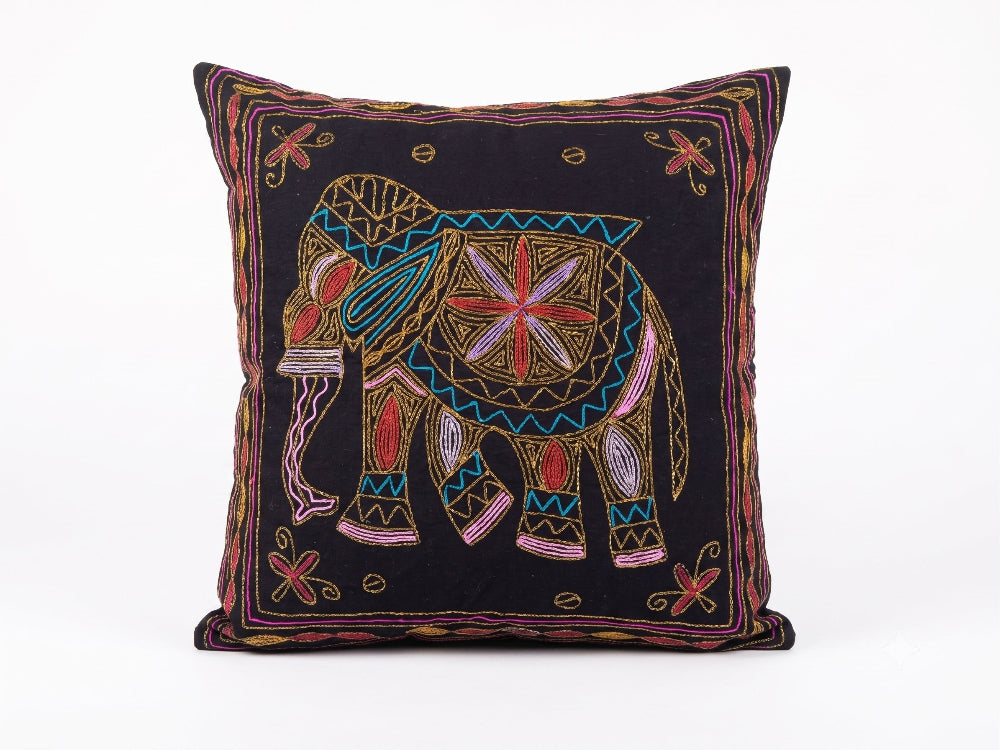A square black throw pillow featuring a colourful embroidered elephant design in the centre with geometric patterns and a decorative border.