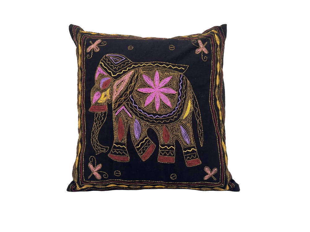 A square black throw pillow featuring a colourful hand-embroidered elephant design in pink, purple, red, and gold on a white studio background.