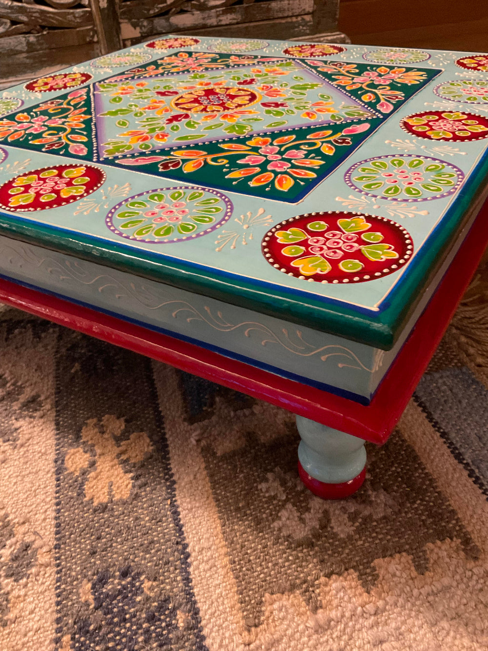Colourful hand-painted table with floral patterns on a textured surface