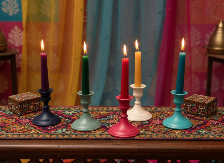 Five colorful candles in various aluminium candle holders on a decorative table with a vibrant curtain background.