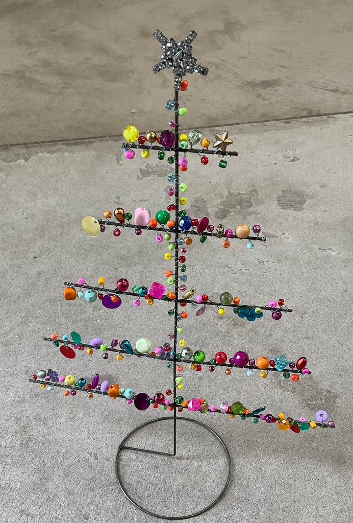 Decorative metal tree with colorful beads on a concrete surface
