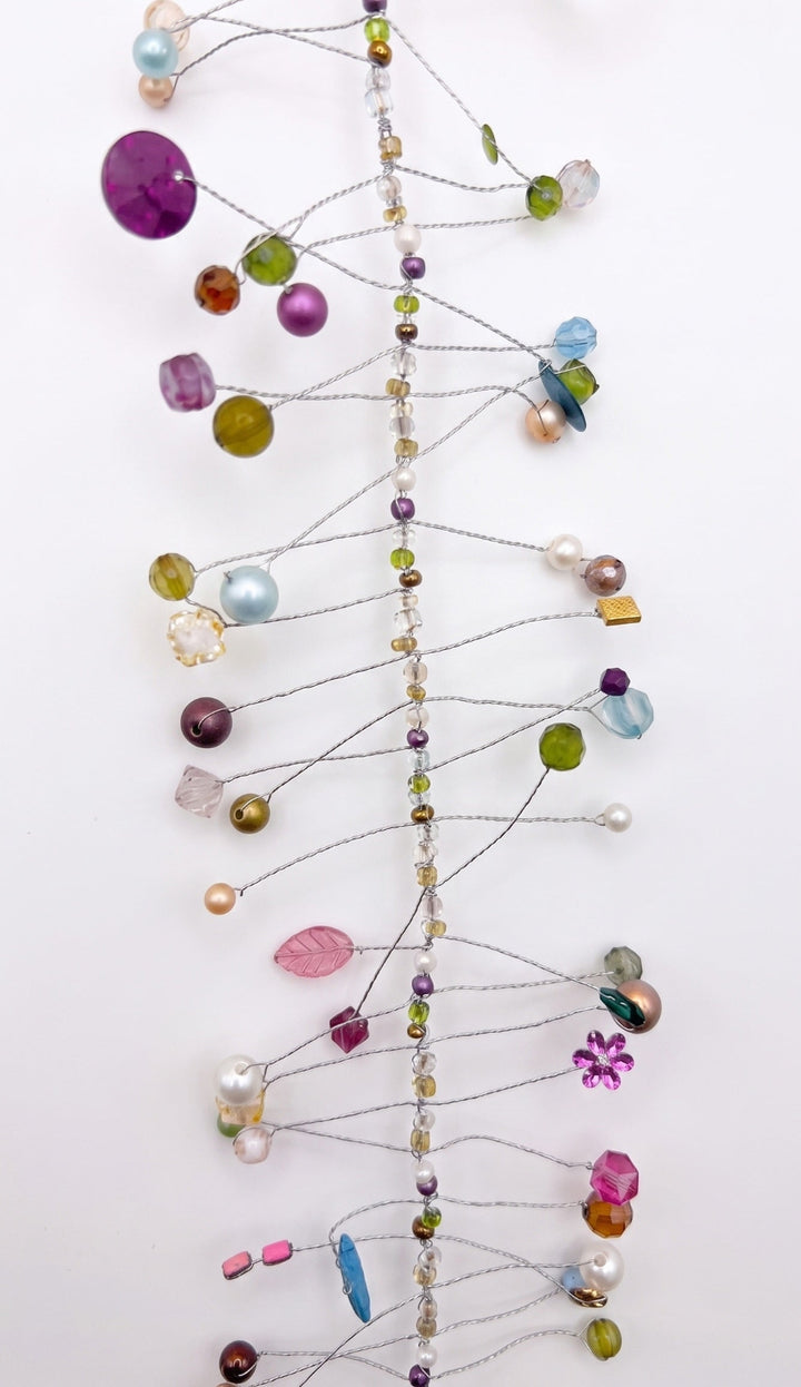 A delicate wire ornament featuring colourful faceted beads, pearls, and glass gems in purple, green, blue, pink, and gold on a white background.