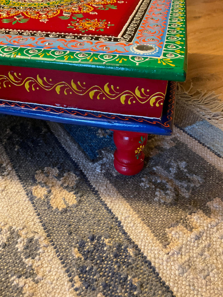 Colorful wooden table with intricate designs on a patterned rug