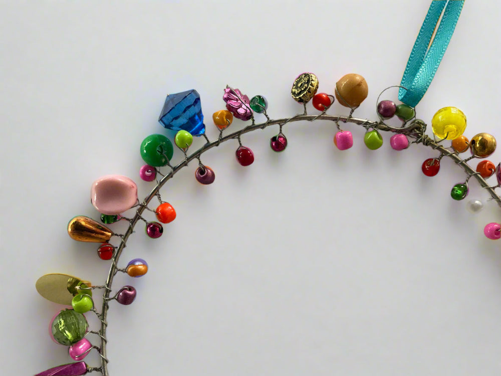 Colorful beaded wreath with a teal ribbon on a white background