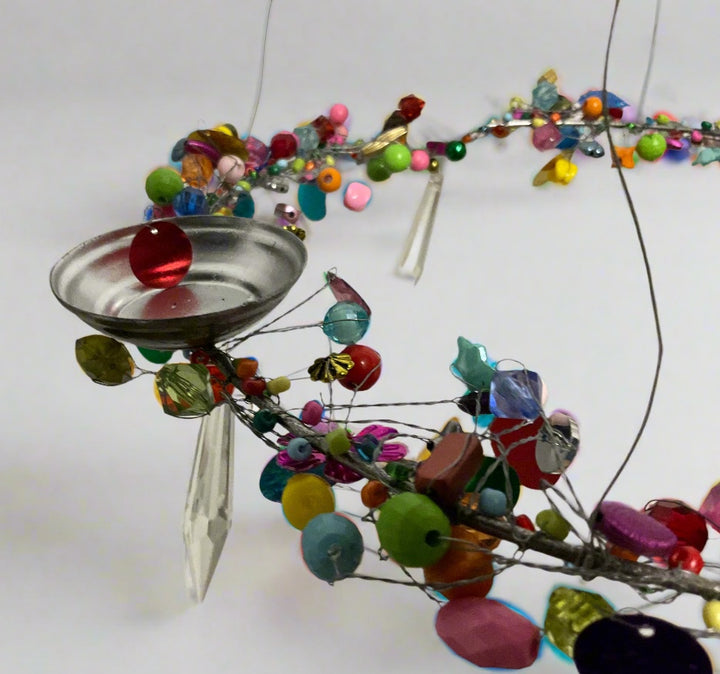 Colourful beaded and metallic decorative object on a white background