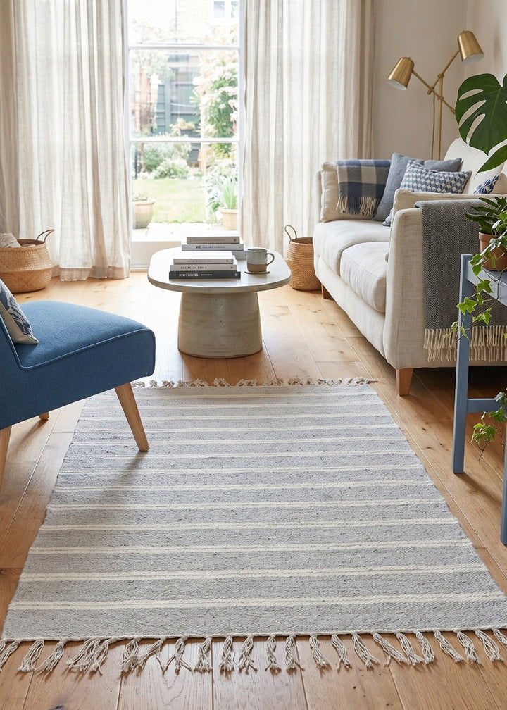 Living room with a striped rug, blue chair, and white sofa.