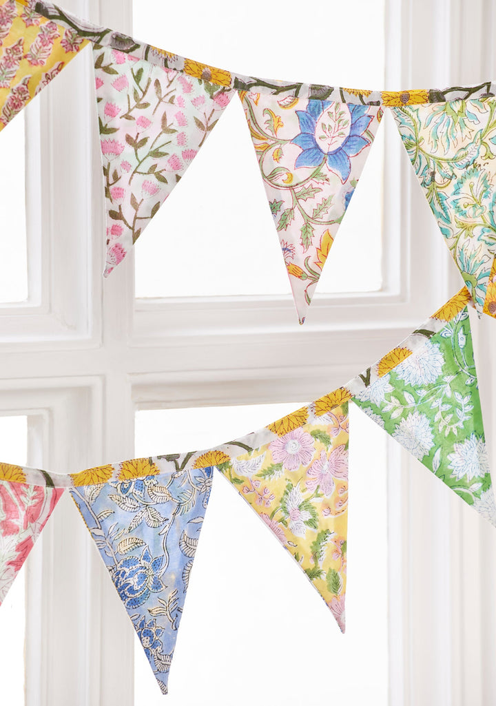 Colourful floral fabric bunting hanging against a white window frame.