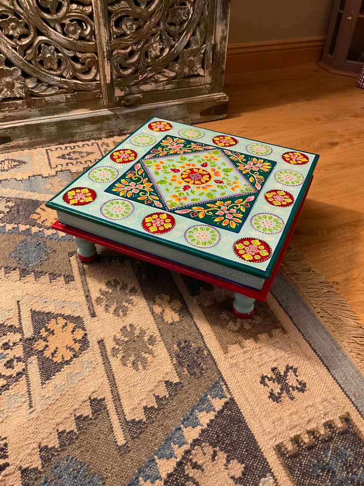 Decorative wooden table with floral patterns on a patterned rug