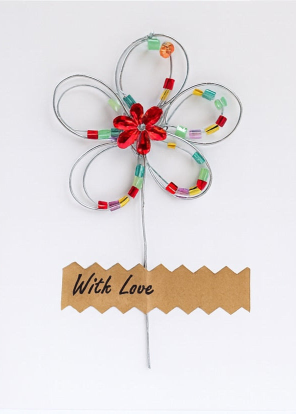 Decorative flower with colorful beads and a red center on a white background, accompanied by a 'With Love' card.