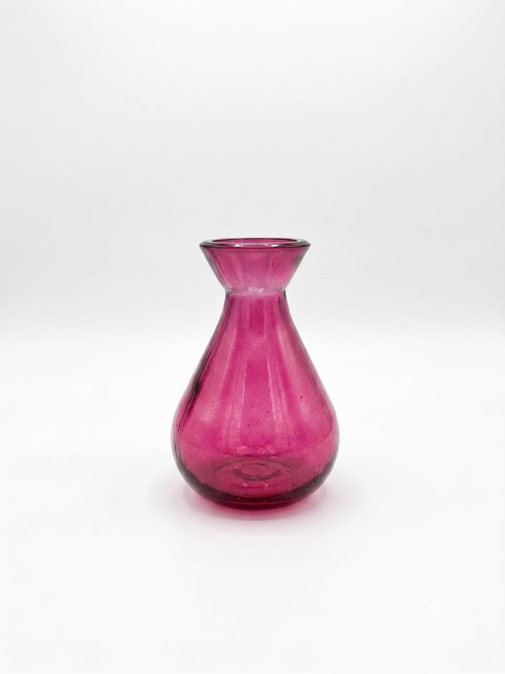 A small translucent pink glass vase with a flared neck and rounded base, photographed against a plain white studio background.