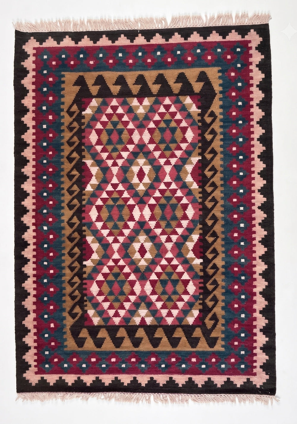 A square kilim area rug with a geometric tribal pattern in pink, red, black, beige, and blue, featuring fringed edges.
