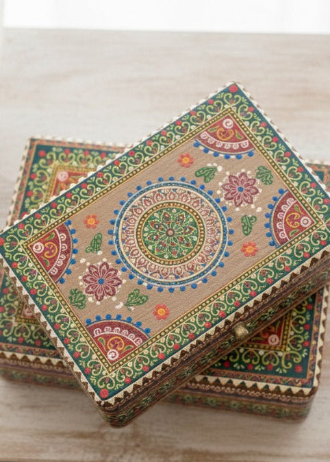 Decorative wooden box with intricate patterns on a light wooden surface.