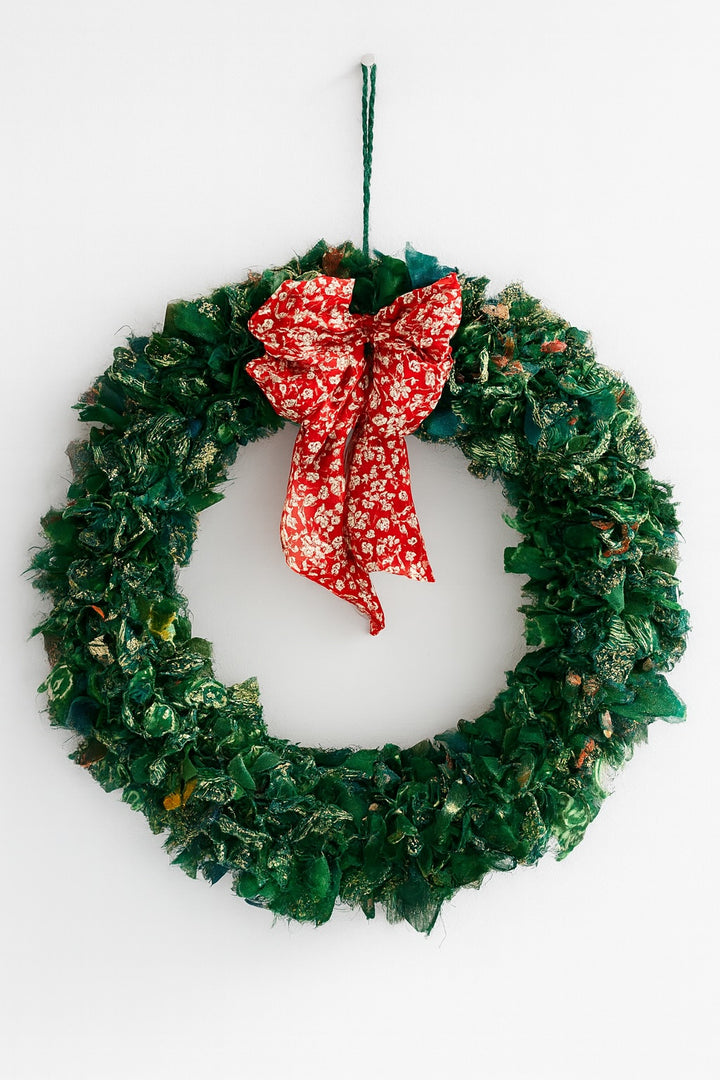 Green Christmas wreath with a red bow on a white background
