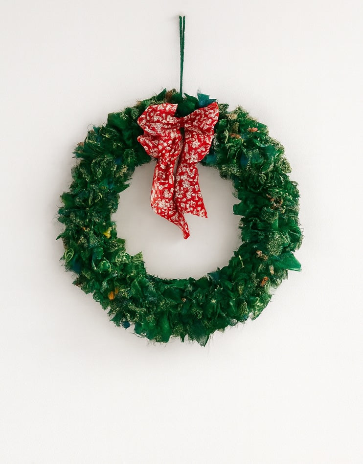 Green Christmas wreath with a red bow on a white background