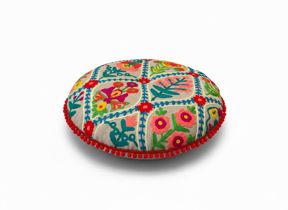 Colourful embroidered round cushion on a white background