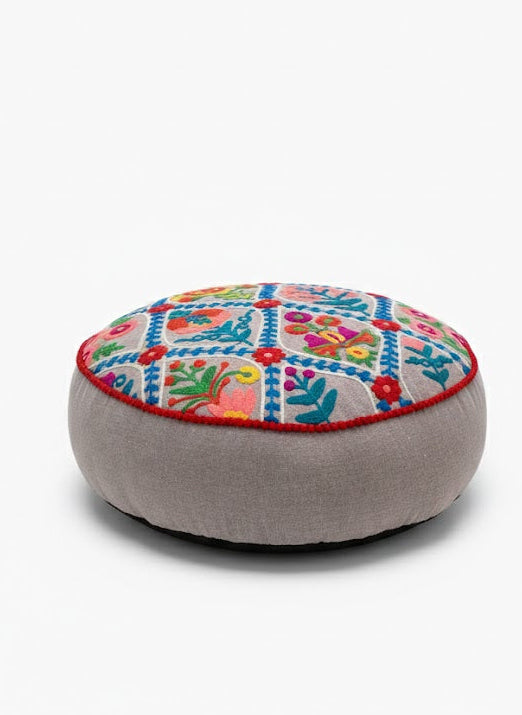 Round natural cushion with colourful embroidery on a white background