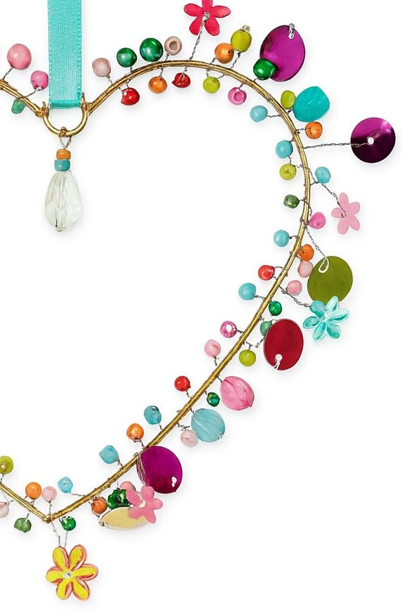Decorative hanging in a heart shape with colourful beads and flowers on a white background