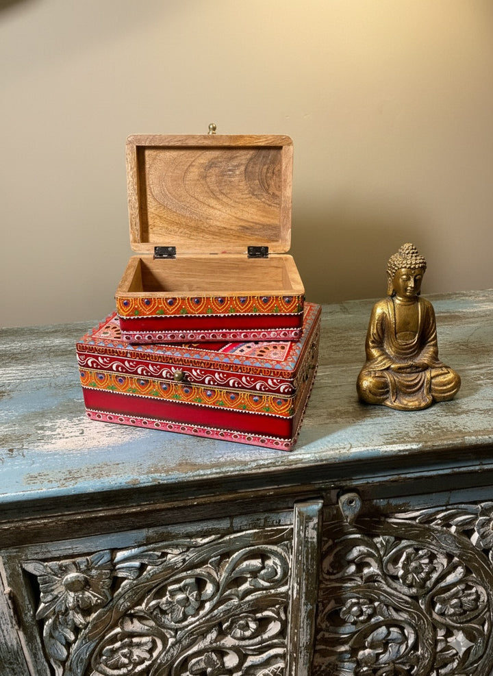 Decorative wooden box with colourful patterns on a rustic surface with a gold Buddha statue.