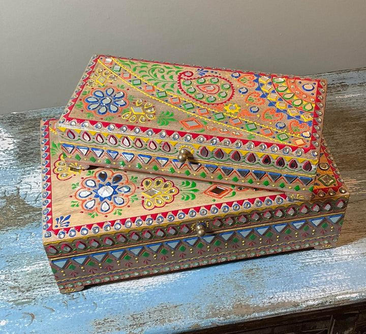 Decorative wooden box with colourful patterns on a wooden surface