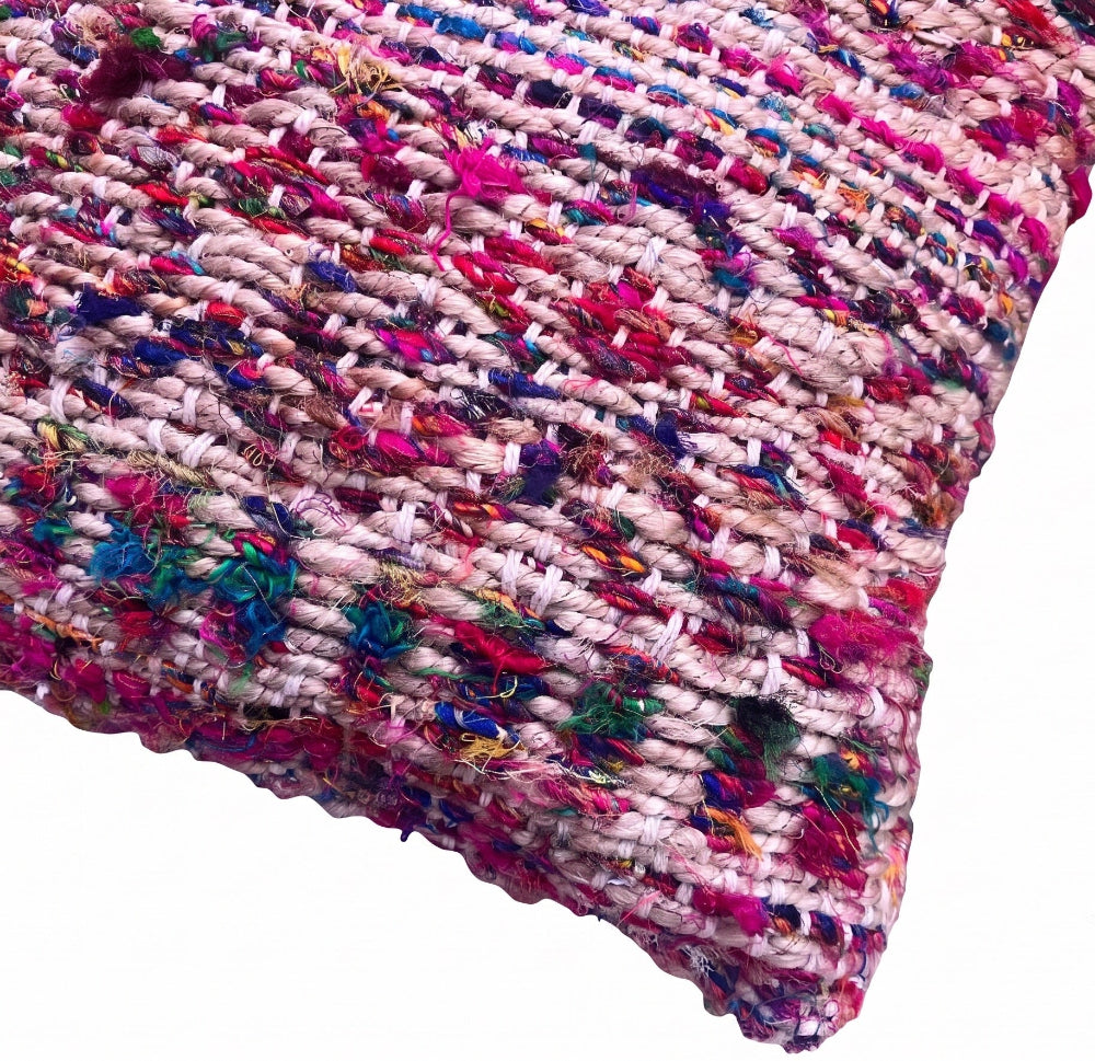 A close-up of a chunky woven throw blanket with a multicolor variegated pattern of pink, purple, blue, green, and white yarns, shown against a plain white background.