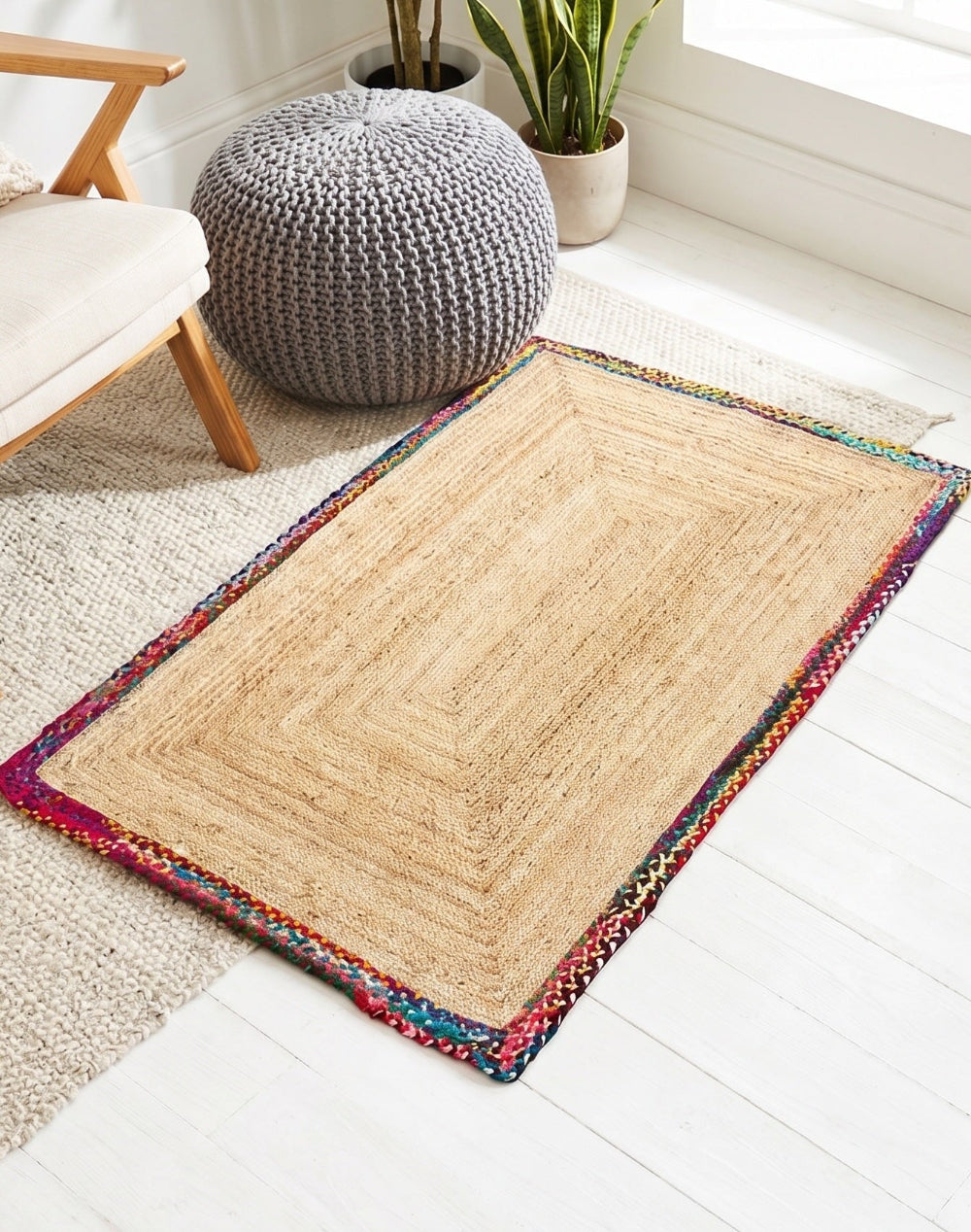 Beige rug with colorful border on a white floor in a room with furniture and plants.