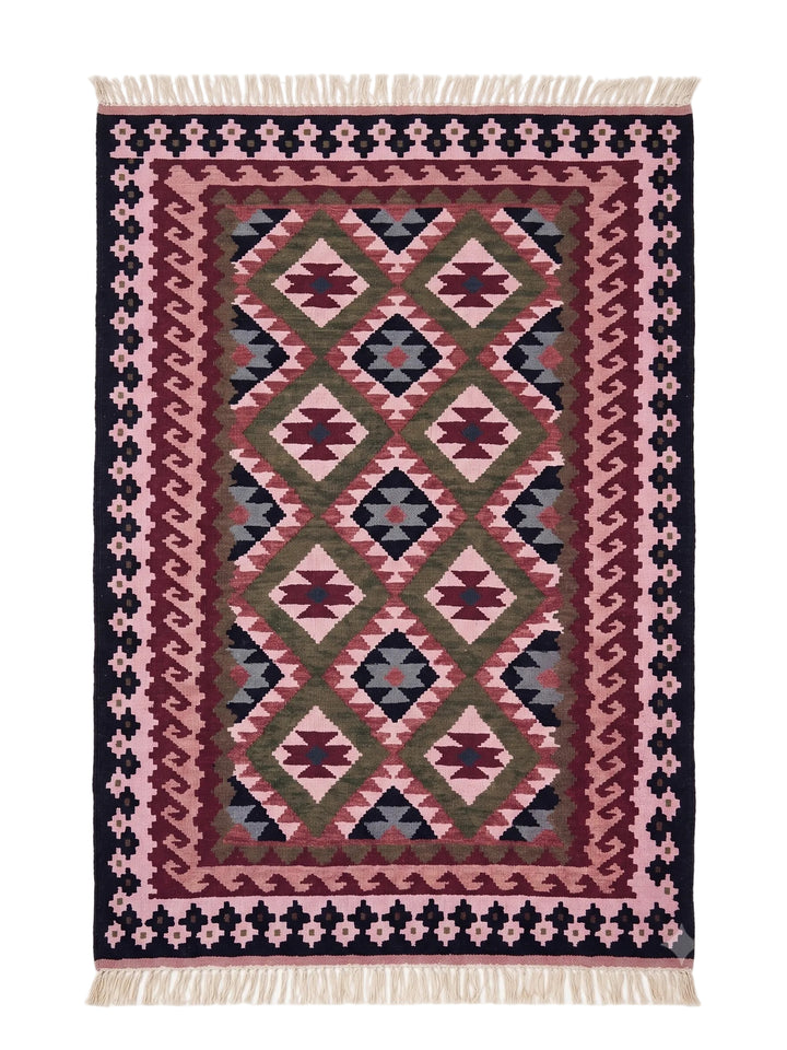 A rectangular woven area rug with a Southwestern geometric pattern in pink, burgundy, olive green, and navy blue, finished with cream-coloured fringe on the top and bottom edges.