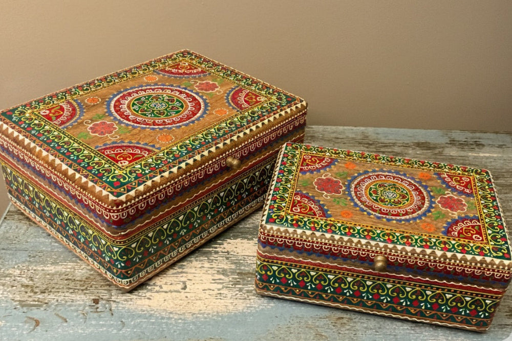 Two ornate boxes with intricate designs on a wooden surface.