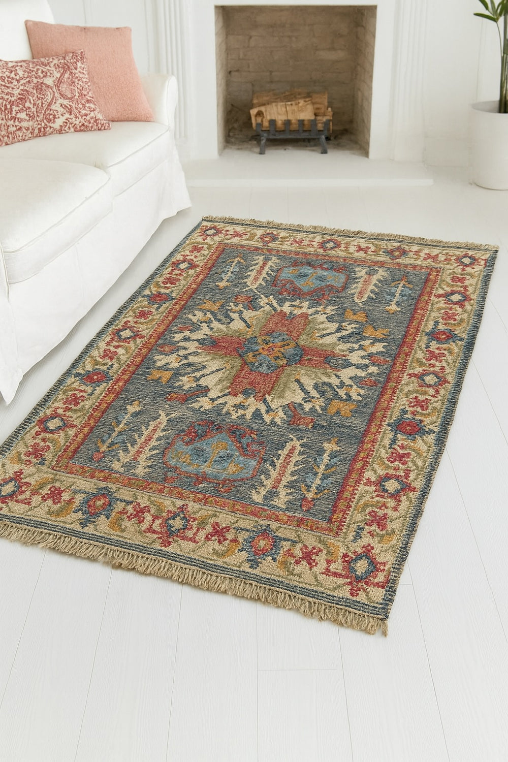 Decorative rug with geometric pattern on a white floor, with a fireplace and sofa in the background.