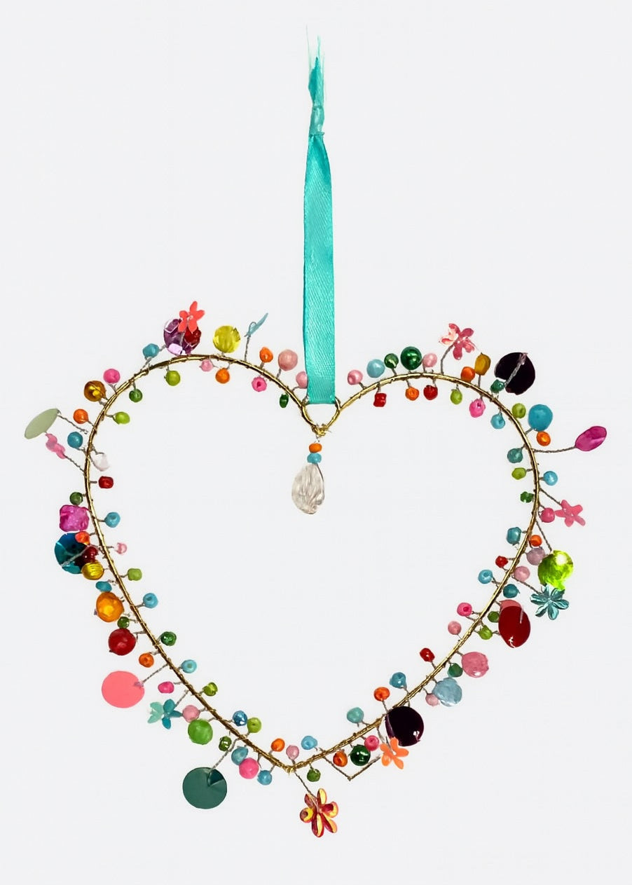 Heart-shaped hanging with coloruful beads and a turquoise ribbon on a white background
