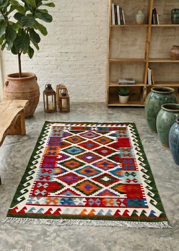 Colourful geometric-patterned rug on a concrete floor with a wooden bench and bookshelf in the background.