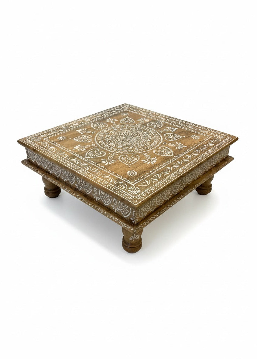 Decorative wooden table with intricate white painted design on a white background