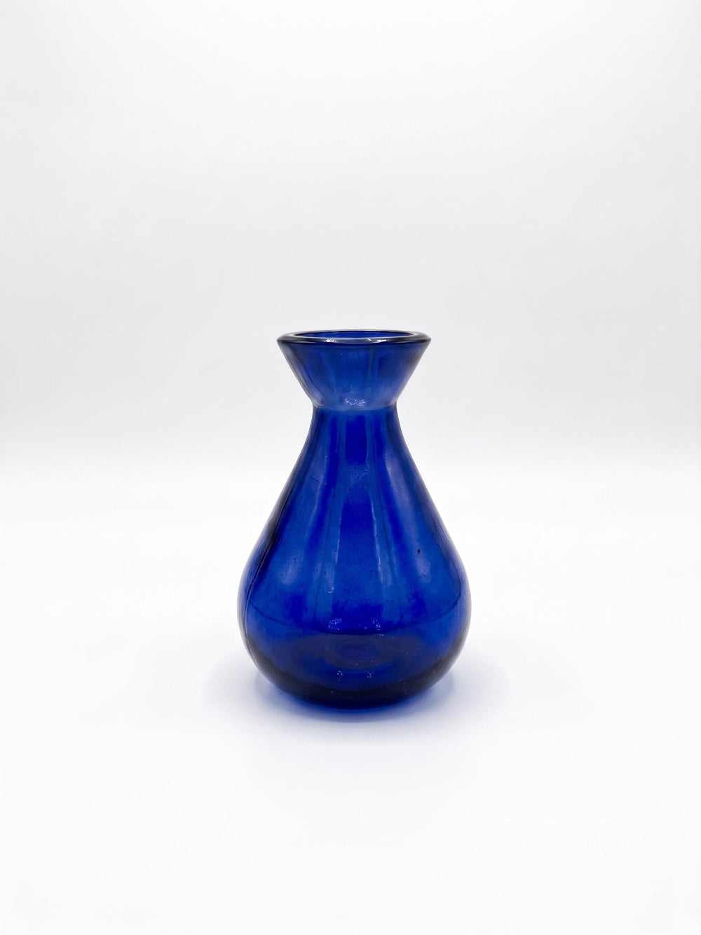 A small cobalt blue glass vase with a flared rim and ribbed body, centered on a plain white studio background.