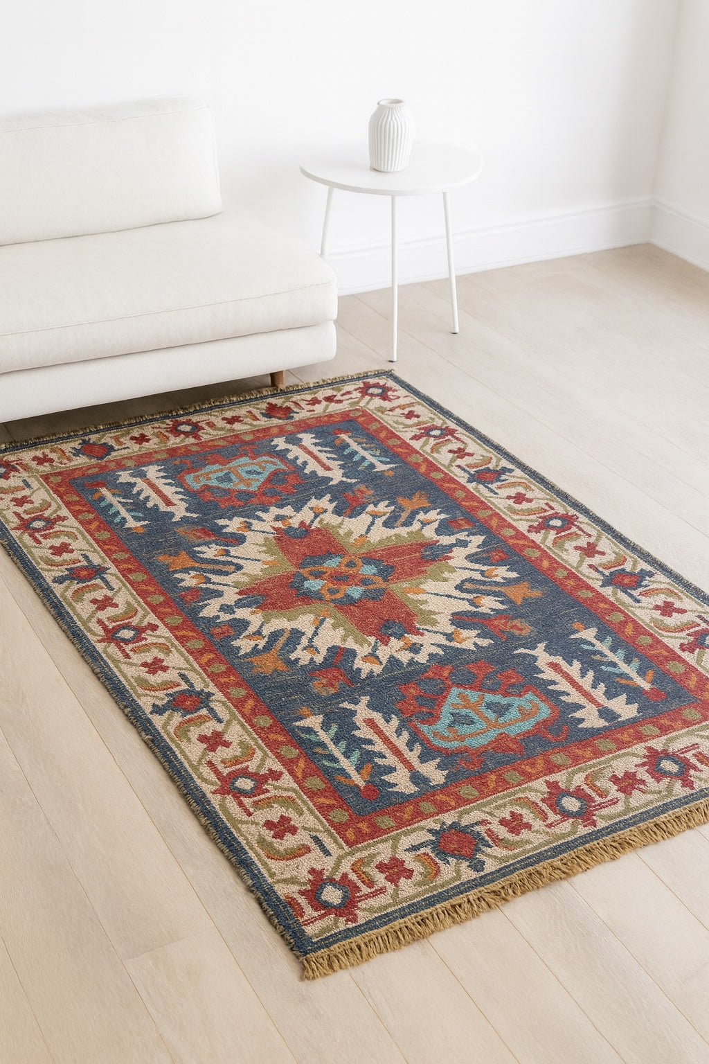 Decorative rug with geometric pattern on a light wood floor in a room with white walls and furniture.