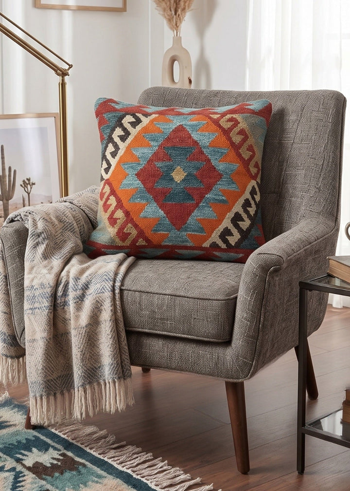 Grey armchair with a coluorful patterned porange terracot cushion in a living room setting.
