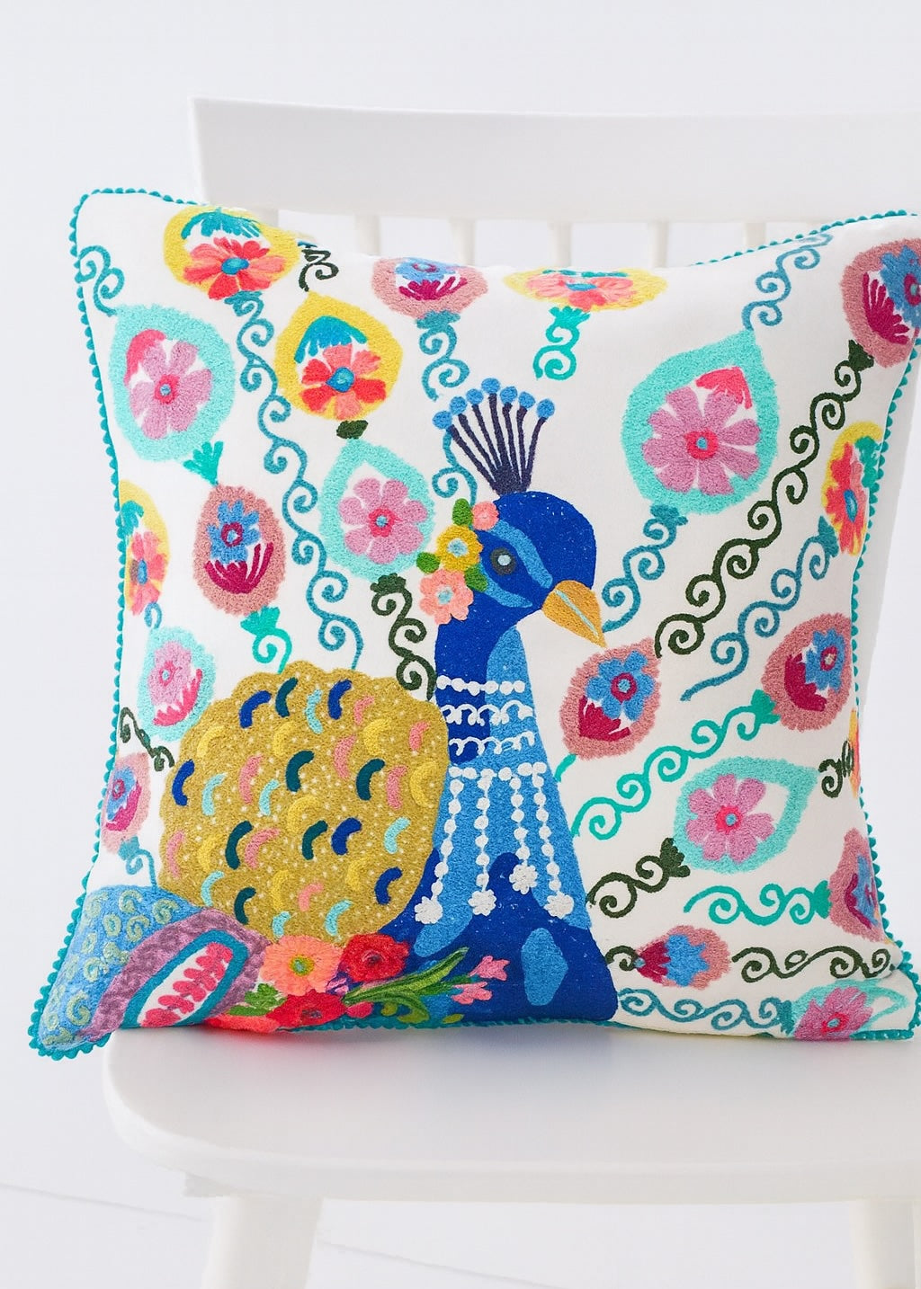 Decorative pillow with a colourful peacock design on a white background
