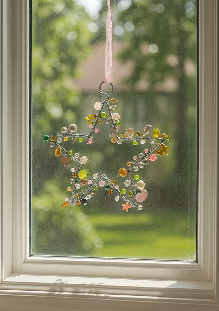 Decorative star hanging on a window with a blurred green outdoor background